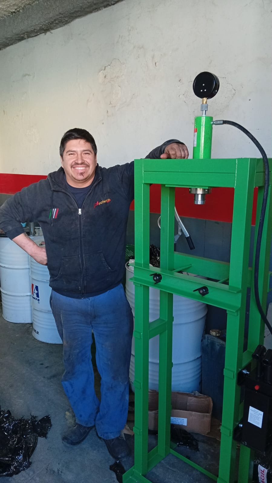Cliente de JD Máquinas y Herramientas junto a una prensa hidráulica verde
